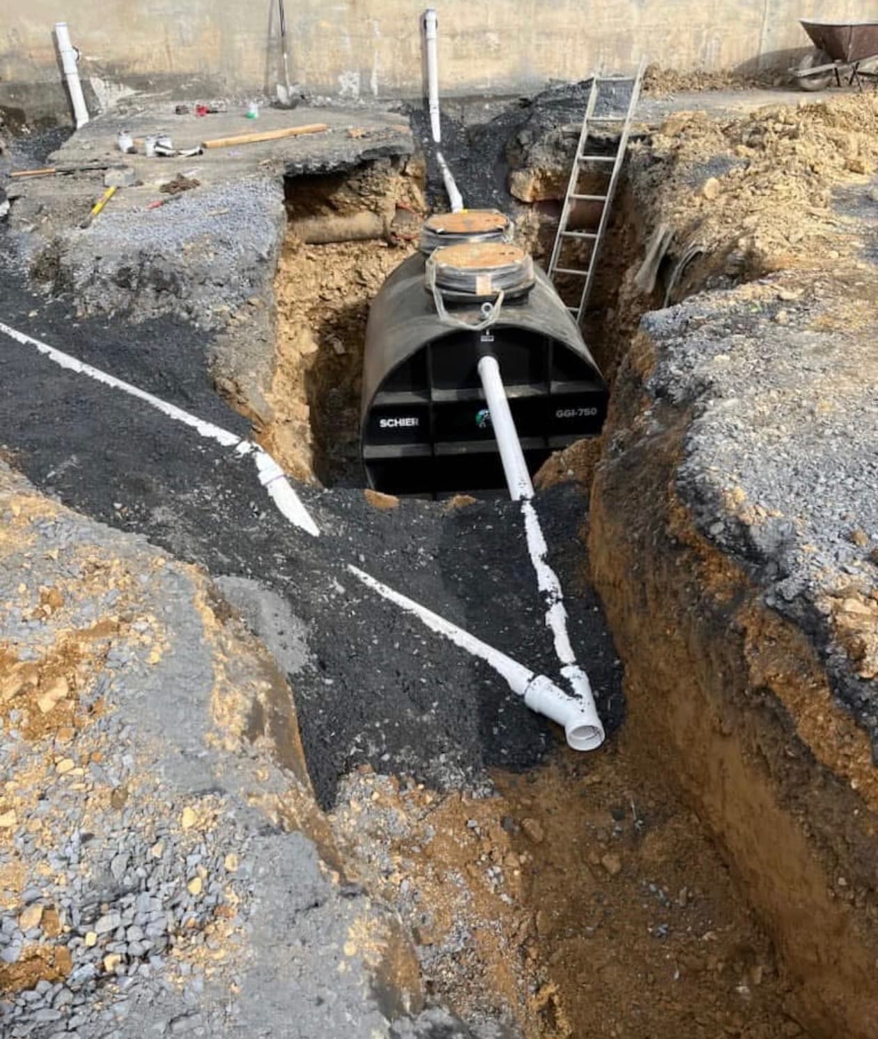 New underground drain lines and a buried tank set in an open excavation
