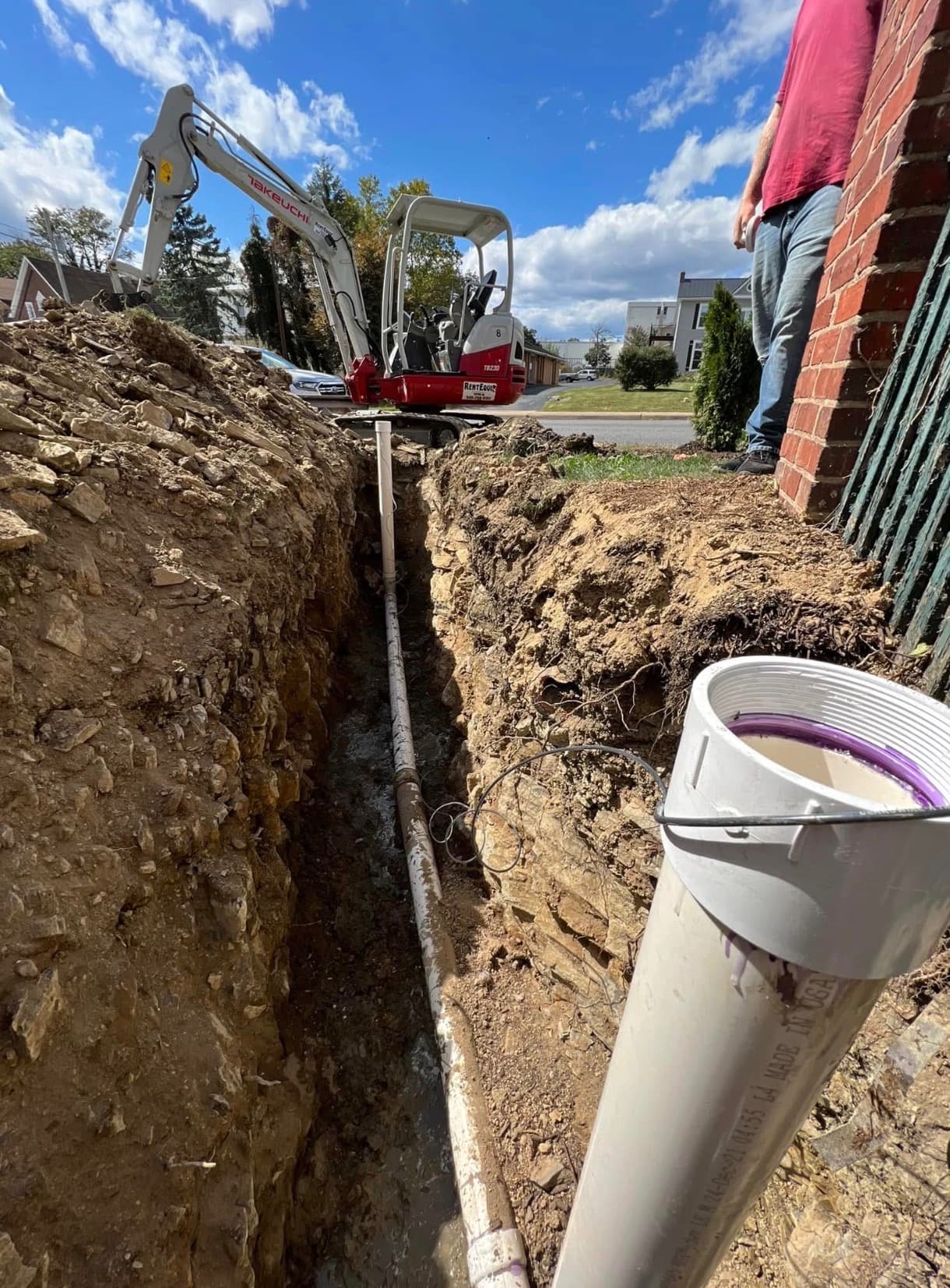 Trenching and replacing an underground line at a brick building