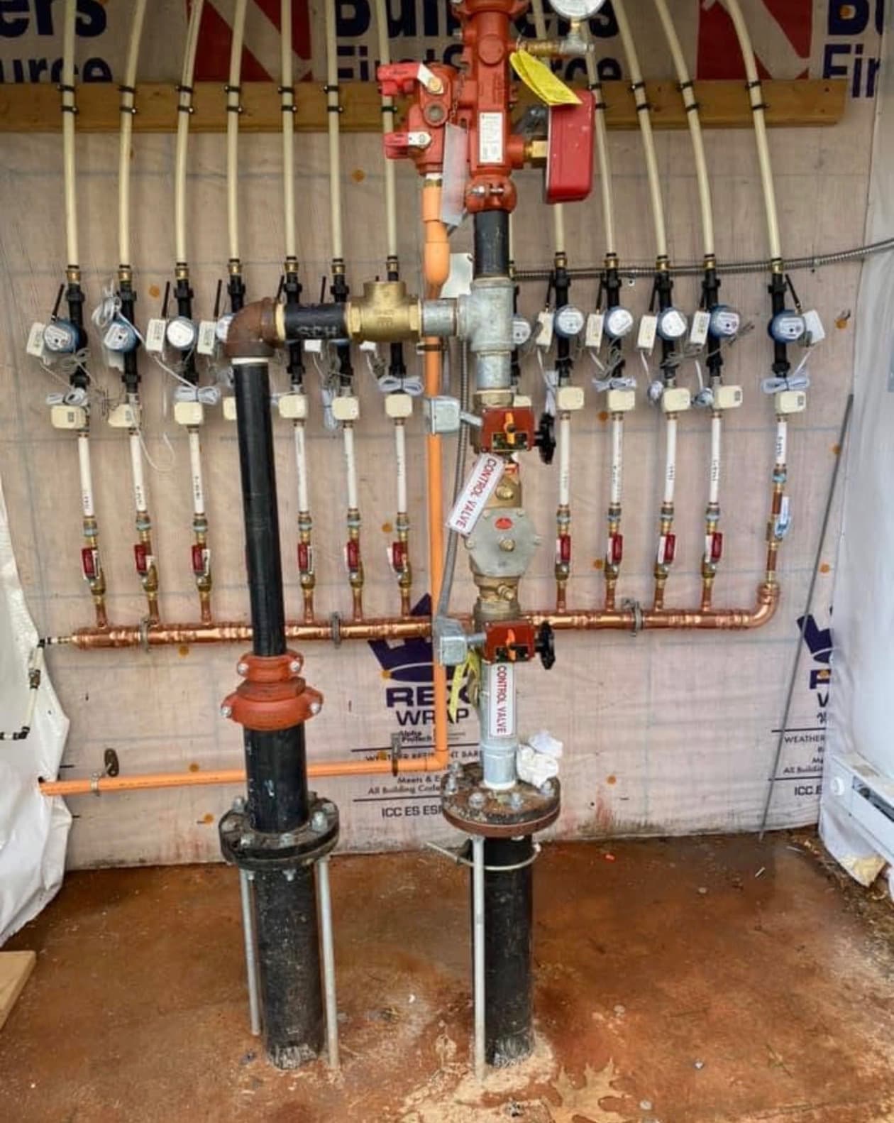 Multi-meter water service wall with backflow prevention in a commercial building